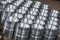Closeup pattern of shiny circular precision stainless steel industrial machine parts arranged in rows on pallet. Steel