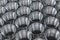 Closeup pattern of shiny circular precision stainless steel industrial machine parts arranged in rows on pallet. Steel