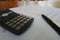 Closeup of a pen and calculator on documents of debts - concept of loans and banking