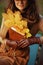 Closeup on pensive woman with brown notebook and yellow leaves