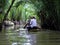 Closeup of people rowing in a long boat in Vietnam mangrove waterways