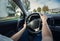 Closeup person hands on the steering wheel, confident driving car on the city streets