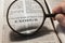 Closeup of a person holding a magnifier and reading the book of Exodus from the New Testament