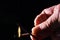 Closeup of a person lighting incense with a match isolated on a black background