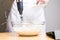 Closeup of a person mixing batter for cheesecake in a bowl on the table