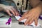 Closeup of a person sewing a purple ribbon on a facemask in the workshop - COVID-19 awareness