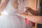 Closeup of a person tying a bow on the back of the bride\'s dress