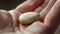 A closeup of a persons hand holding a small smooth stone or crystal. The persons fingers gently trace the curves and