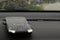 Closeup of a phone on the dashboard of a car with raindrops on the front windshield