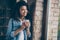 Closeup photo of amazing dark skin curly lady holding hot coffee drink looking window leaning brick wall wear casual