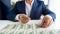 Closeup photo of businessman sitting behind desk and laying money in straight rows