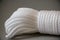 Closeup photo of Coiled white Nylon Rope on gray background.