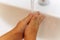 Closeup photo of faceless kid washing hands under running water from a tap before taking a bath, hygiene procedures, hands of