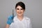 Closeup photo of female dentist holding oral syringe isolated over the grey backgrownd.