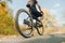 Closeup photo, focus on bike wheel. Rear view. Cyclist walks by bike in the autumn forest, stopped to rest and see the beautiful