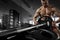 Closeup photo of handsome bodybuilder guy prepare to do exercises with barbell in a gym, keep barbell plate in hands