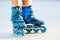 Closeup photo of legs in blue inline skates standing.