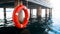 Closeup photo of red saving ring hanging wooden pier. Safety on sea water