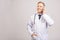 Closeup photo of senior man doctor standing isolated on grey background, using mobile phone