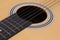 A closeup photo of the sound hole body of an acoustic guitar