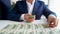 Closeup photo of successful businessman laying money in front of him on office desk