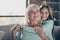 Closeup photo of two best friends people cute aged granny small grandchild girl sit comfortable sofa hug piggyback