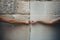 Closeup photo of two hands holding each other in front of stone wall. Concept of Israeli-Palestinian conflict