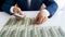 Closeup photo of wealthy businessman laying US dollars banknotes on office desk in long rows