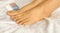Closeup photo of woman feet on a white towel with nail polish bottle beside