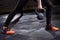 Closeup photo of young woman`s legs in leggings and sneackers and kettlebell against dark background.