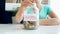 Closeup photo of young woman sitting behind desk and holding glass jar with money savings