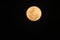 A closeup photograph of a rare orange full moon in a pitch black sky