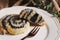 Closeup picture of a bitten delicious Poppy snail pastry with a sugar glaze on a white plate