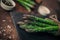 Closeup picture of fresh asparagus bunch on top of a slate chopper