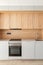 Closeup of piece of modular kitchen furniture made of light wood. Modern cozy kitchen interior with appliances built