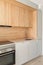 Closeup of piece of modular kitchen furniture made of light wood. Modern cozy kitchen interior with appliances built