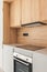 Closeup of piece of modular kitchen furniture made of wood. Modern cozy kitchen interior with appliances built into