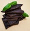 Closeup pieces of dark, inferior chocolate and green basil leaves