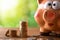 Closeup piggy bank with coins on table and nature background