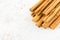 Closeup of a Pile of Cinnamon Sticks over White Speckled Background with Copy Space