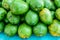 Closeup of pile of green mangoes on turquoise table