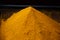 Closeup of a pile of turmeric powder under the lights with a blurry background