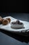 Closeup of a pile of walnut-filled chocolate confections on a small plate.