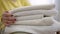 Closeup pile of white clean towels with female young hands caressing cloth. Unrecognizable Caucasian happy woman