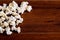 Closeup pile of white fluffy popcorn lying mixed together on wooden surface