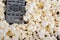 Closeup pile of white fluffy popcorn with tv remote control in the middle