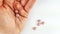 Closeup of pink pills tablets as medical drug on palm hand and on the white background table, counting the dose of painkillers or