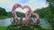 Closeup Pink Statue of Large Cut Hearts on Flowerbed by Lake