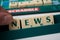 Closeup of plastic letters with word news in hand on Scrabble board game