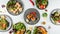 Closeup of the plates of sushi with fresh vegetables on the white table